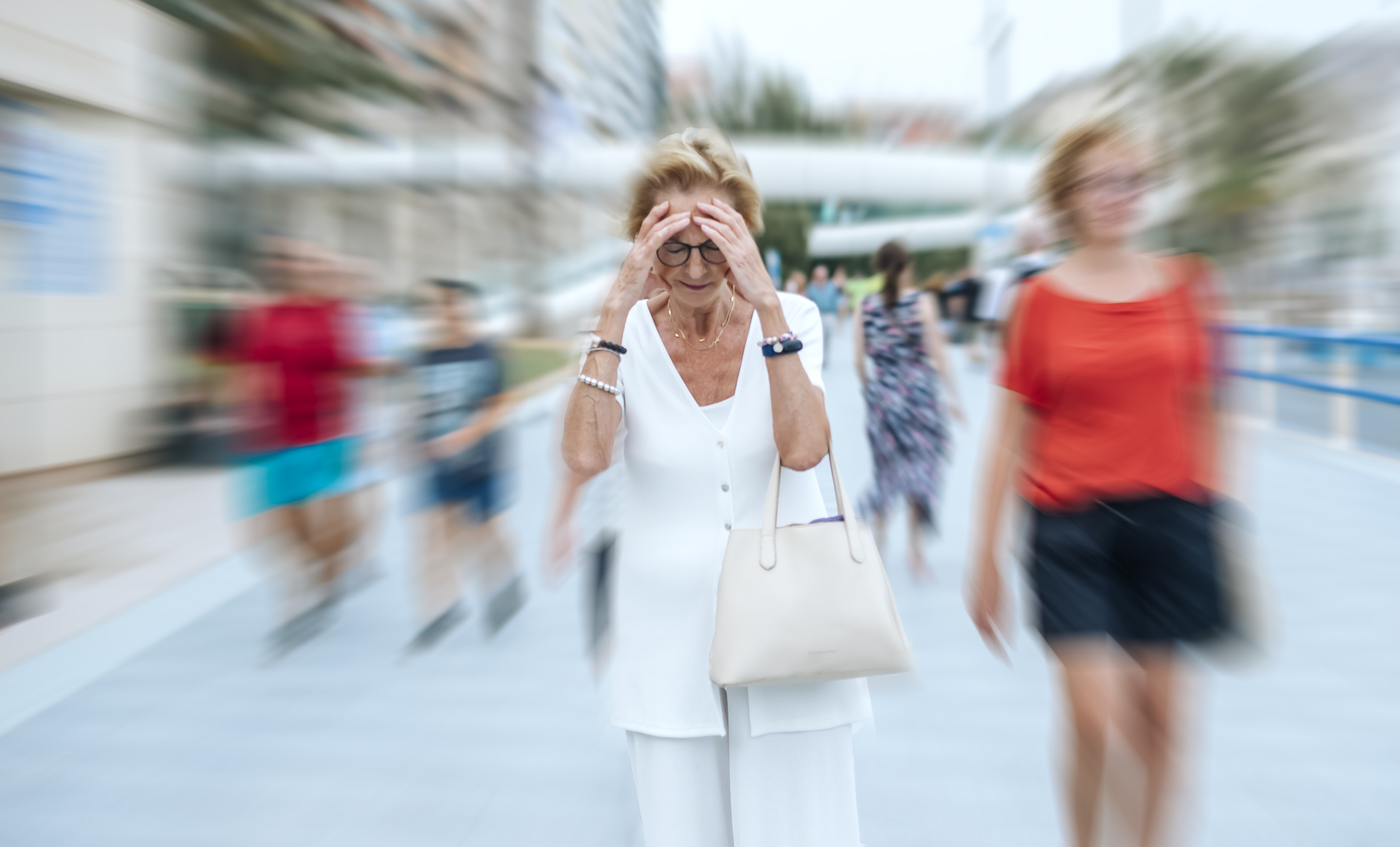 An older woman on the street with her hands on her head feels overcome. Concept of mental health